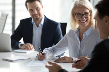 Poster - Smiling mature businesswoman signing contract, agreement at meeting