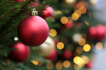 red christmas balls on a fir branches on festive lights background, night illumination. new year tre