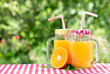 Two Jars Of Orange Juice And Half An Orange