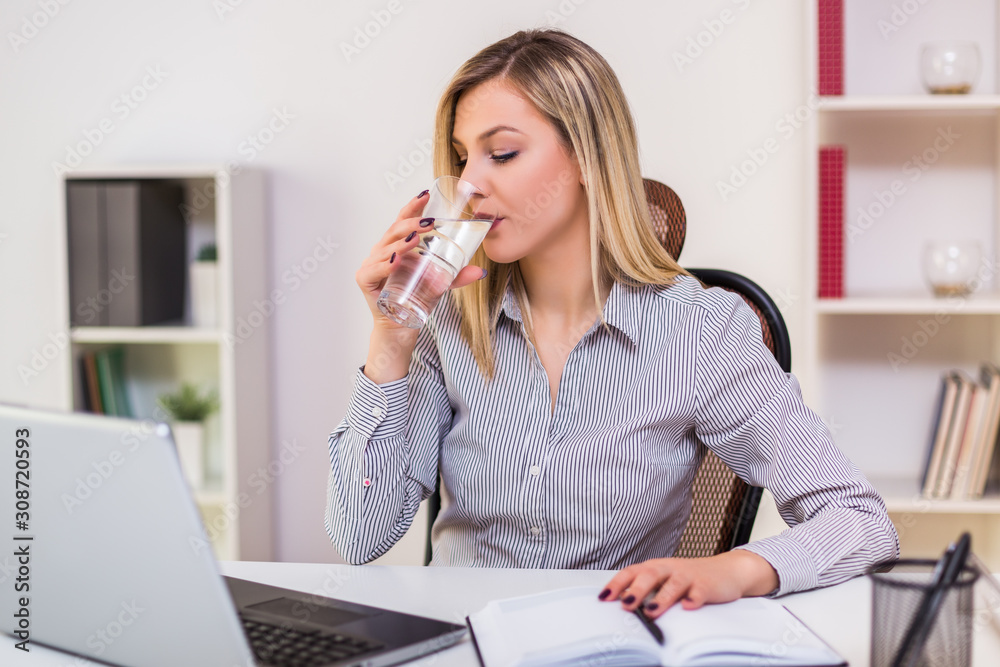 Businesswoman drinking water while working in her office.