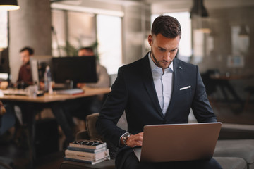 Portrait of handsome businessman. Man with his lap top in office. 