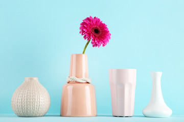 Wall Mural - Different ceramic vases and gerbera flower on blue background