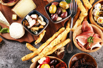 Italian antipasti wine snacks set. Cheese variety, Mediterranean olives, seafood salad, Prosciutto di Parma, tomatoes, anchovy and wine in glasses