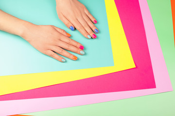 Neon manicure on different multicolored neon backgrounds. Flat lay style.