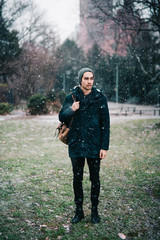 Wall Mural - Young man standing in the park while snowing