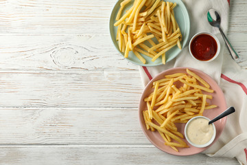 Wall Mural - Plates of french fries, napkin, sauces, forks on black background, space for text. Top view