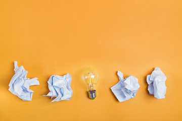 Ideas concepts with lightbulb and paper crumpled ball on bright yellow color background