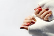 © ita_tinta_ - Autumn manicure in orange, brown and gold color on the white background. Warm atmosphere. Manicured woman's hands in warm white sweater.