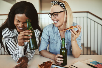 Wall Mural - Laughing young businesswomen drinking beers and having pizza aft