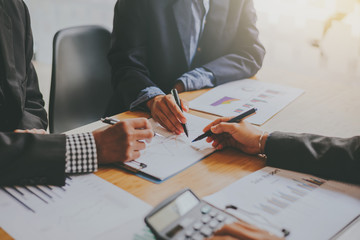 Wall Mural - Business people gather to analyze marketing and investment information and using pen pointing to financial data chart at meeting.