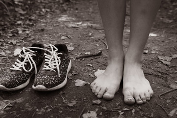 Wall Mural - bare feet stay tiptoe and trainer shoes close up black and white photo