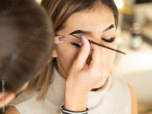 Eyebrow tinting. Close up master applying brow tint with a brush. Cosmetic procedures, eyebrow permanent makeup