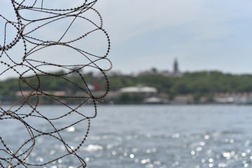 barbed wire on the blur background of the river and the city promenade