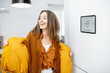 © rh2010 - Happy woman taking off her outerwear by coming to a warm home. Concept of a smart home and remote heating control over the internet