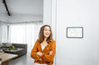 © rh2010 - Portrait of a young and happy woman standing near touch screen panel for smart home control in the hallway at home