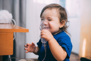 a little girl yourself holding the mask of the nebulizer, making inhalation