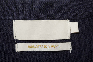 Wall Mural - 100 merino wool label on the sweater dark blue wool fabric.