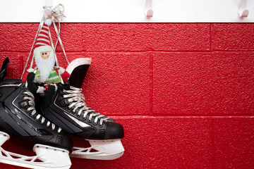 Wall Mural - Christmas background of hockey skates with elf hanging over red wall with copy space 