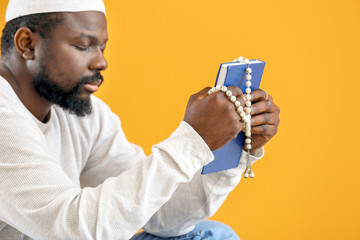 Wall Mural - African-American Muslim man with Koran and beads on color background