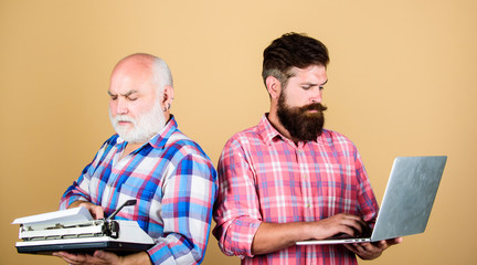 competitors. father and son. family generation. technology battle. Modern life. retro typewriter vs laptop. New technology. youth vs old age. business approach. two bearded men. Vintage typewriter