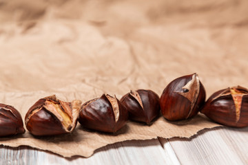 Roasted chestnuts on paper on a wooden background