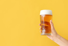 Hand With Glass Of Beer On Color Background