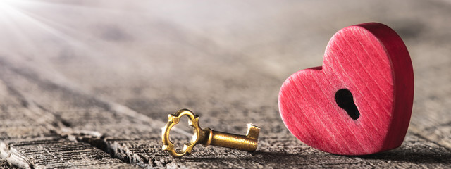 Wall Mural - small rustic red heart with shiny golden key on wooden table - valentine's day concept