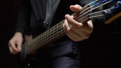 man plays the bass guitar. Dark background. slowmo