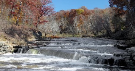 Wall Mural - Seamless loop features the water of Mill Creek rushing over Lower Cataract Falls, a wide waterfall in rural Owen County, Indiana with autumn foliage colorful