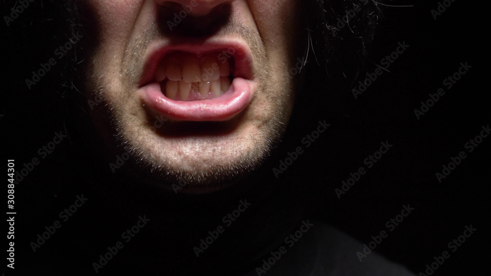 closeup. male mouth with crooked teeth screaming. Black background. - obrazy, fototapety, plakaty 