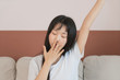 © xxxstudio - Young bored woman yawning at home covering mouth with hand
