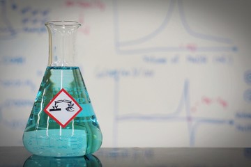 Erlenmeyer flask with Bright blue liquid and chemical hazard warning symbols labels (corrosive symbol) on whiteboard with chemical learning background.