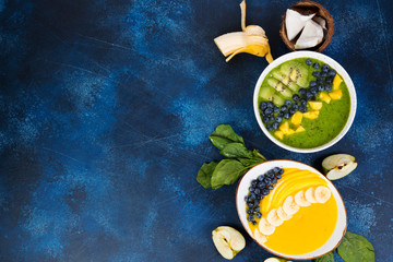 Two cups of different smoothie bowl of green and yellow fruits. The concept of healthy eating. Horizontal photo with copy space. Top view.