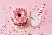 Stack Of Colorful Donuts Decorated And Glass Of Milk On A Pink Background