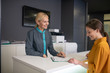 © zinkevych - Blond receptionist in clinic talking to a visitor