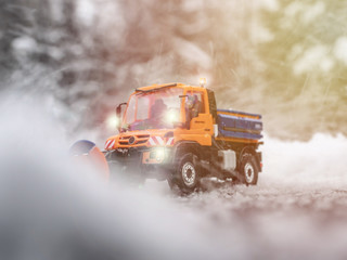 Wall Mural - Snow plow on the road. Scale model 1:87. Winter on the road. Orange truck on snowy road. Orange snow plow on road.