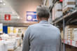 © flowertiare - Tall gray-haired man shopper walking with trolley in a large hardware store before christmas. Back view