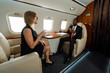 © LIGHTFIELD STUDIOS - happy businesswoman in glasses pointing with finger near african american businessman in private plane