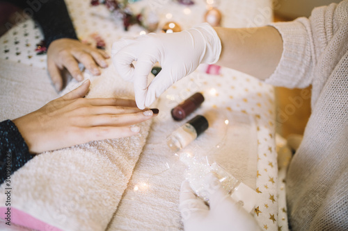 Fotografía Beautician pouring white brocade over woman's nails