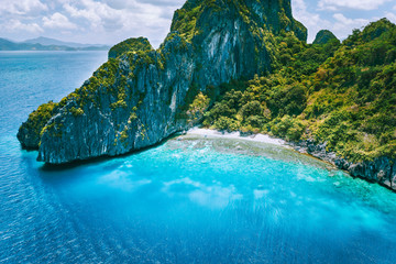 Wall Mural - El Nido, Palawan. Aerial drone view of tropical Entalula Island. Huge steep rocks cliffs mountains with blue bay and beautiful intact coral reef. Island hopping tour trip