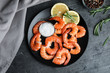Delicious cooked shrimps with lemon and salt on dark grey table, top view