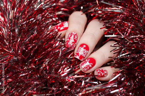 Fotografering red Christmas manicure with deer and snowflakes and Norwegian pattern on the bac
