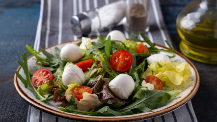 Wall Mural - Vegetarian salad with  tomato, arugula, lettuce and mozzarella cheese on a plate. Healthy and diet food. Concept food