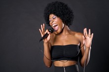Woman Singing On Microphone Over Colored Background