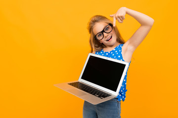 Wall Mural - Nice little girl with her glasses holds a laptop and smiles isolated on white background