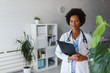 © lordn - Portrait of female African American doctor standing in her office at clinic