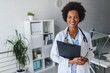 © lordn - Portrait of female African American doctor standing in her office at clinic