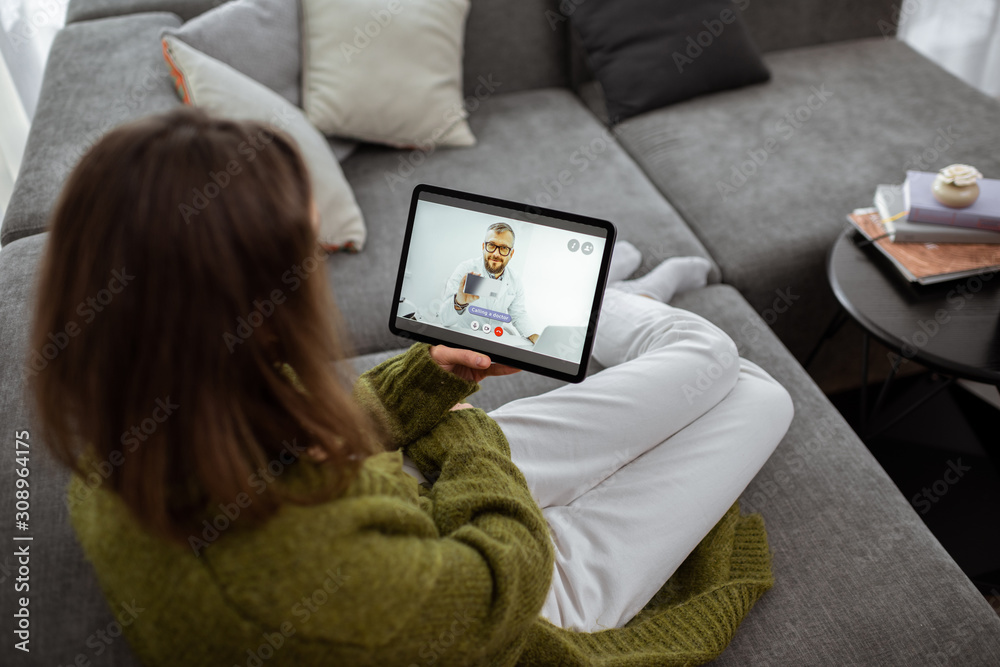 Woman talking with a doctor online using digital tablet, feeling bad at home. Concept of telemedicine and patient counseling online - obrazy, fototapety, plakaty 