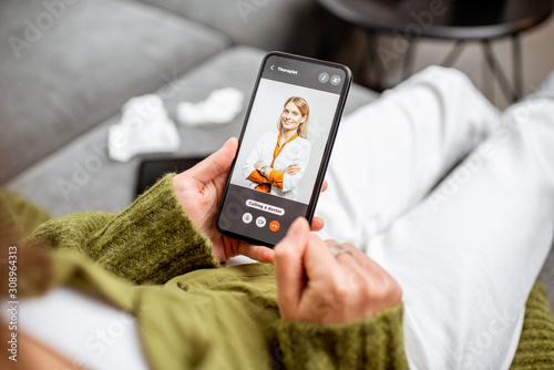 Fotomural Woman talking with a doctor online using smartphone, feeling bad at home, close-up on phone screen