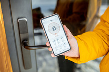 Locking Smartlock On The Entrance Door Using A Smart Phone Remotely. Concept Of Using Smart Electronic Locks With Keyless Access